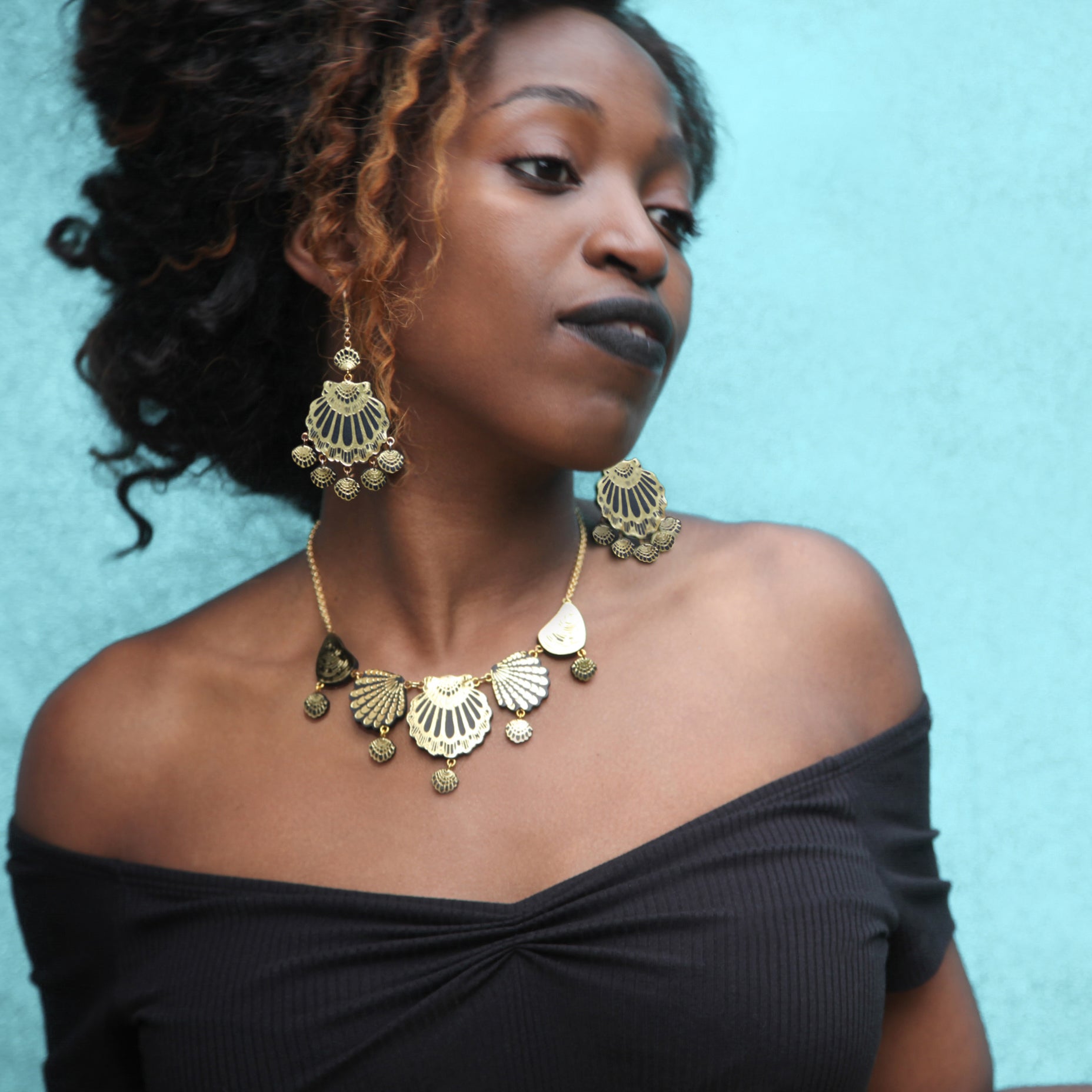 seashell chandelier earrings in black leather with gold printed detail, on model with matching seashell necklace