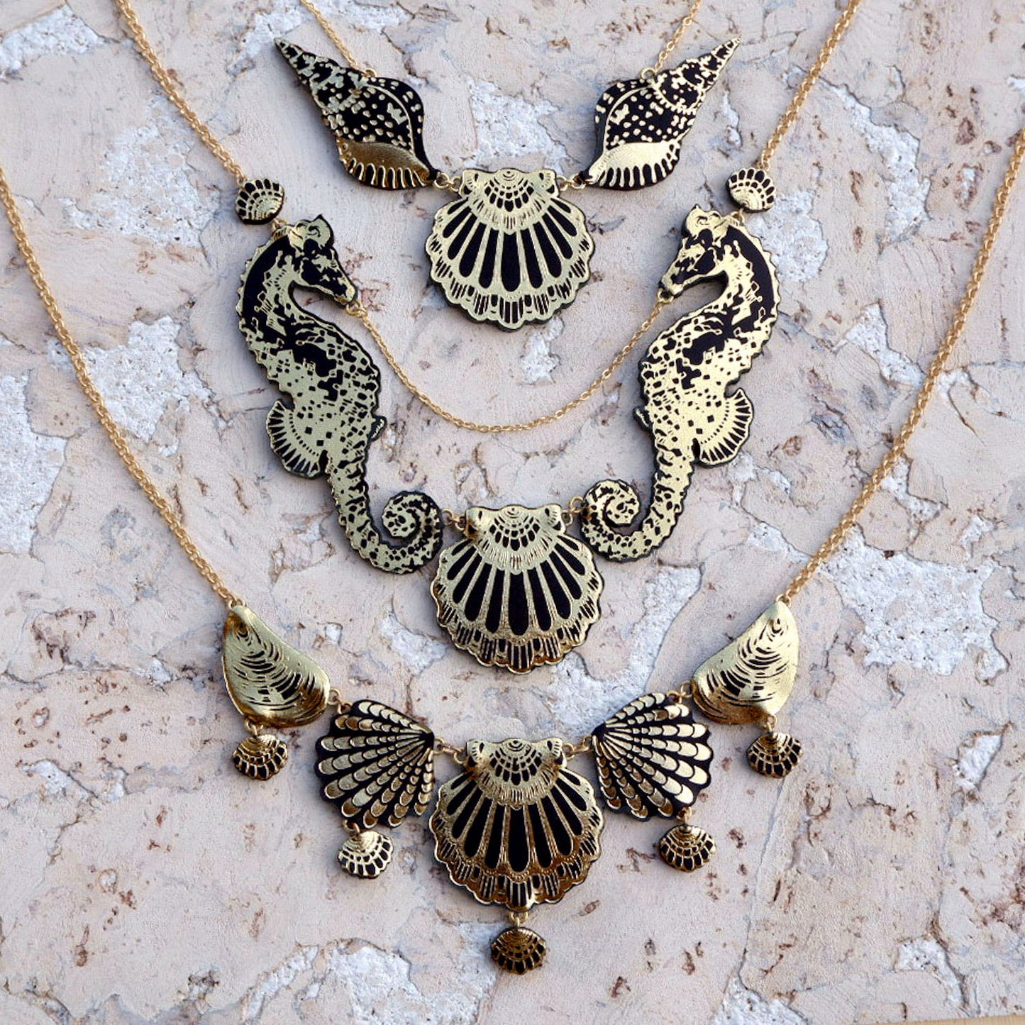 3 necklaces, made of black & gold printed leather sea shells & seahorses, on gold chain