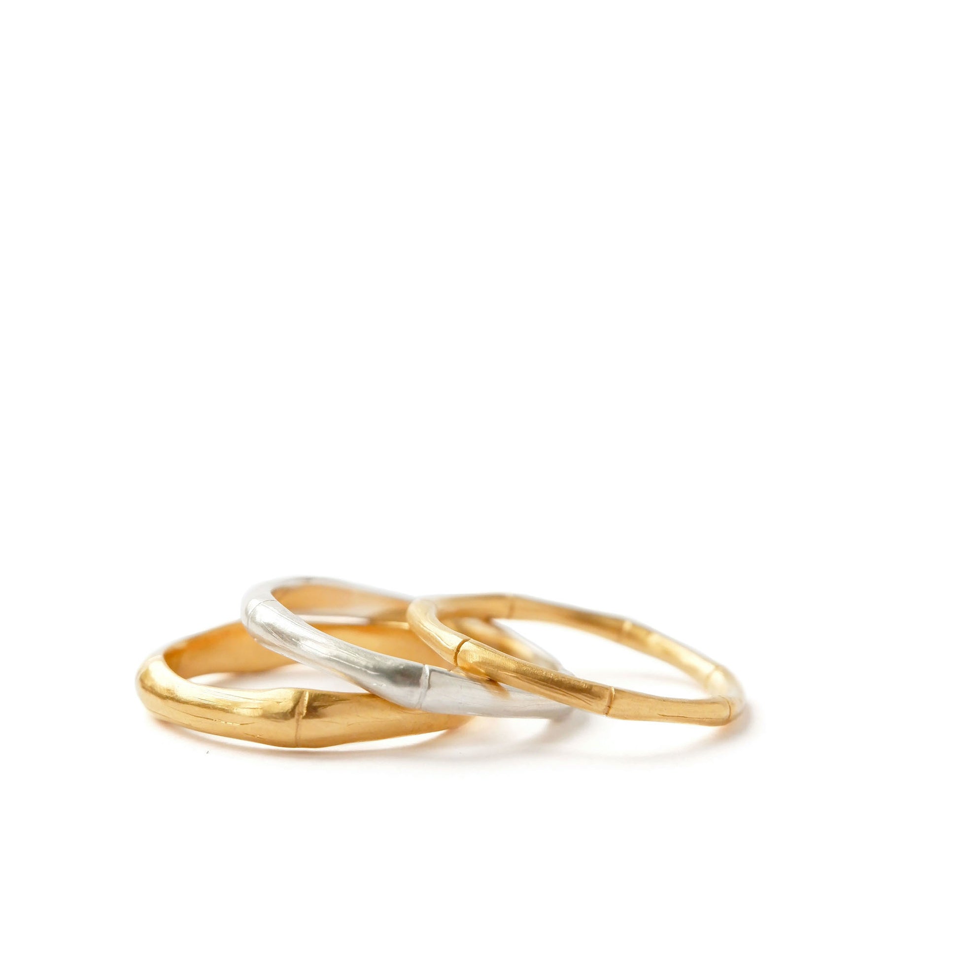 A pile of three bamboo style stacking rings, in three thicknesses in Sterling Silver & Gold Vermeil, white background