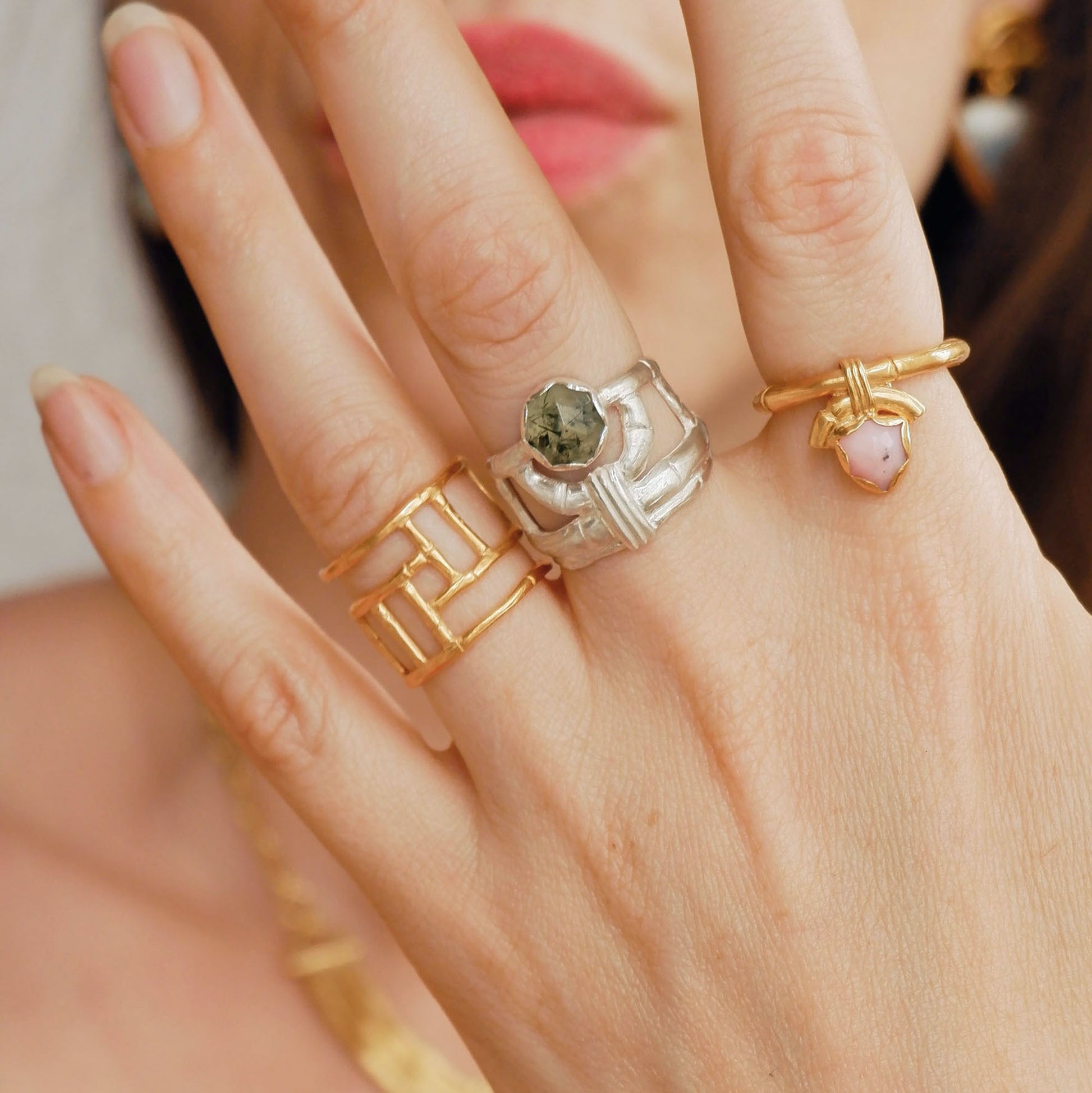structural open-work ring in a bamboo style, featuring a faceted round green rutilated Prehnite gemstone in a scalloped setting. Sterling Silver. Shown on hand for scale, with 2 gold bamboo rings