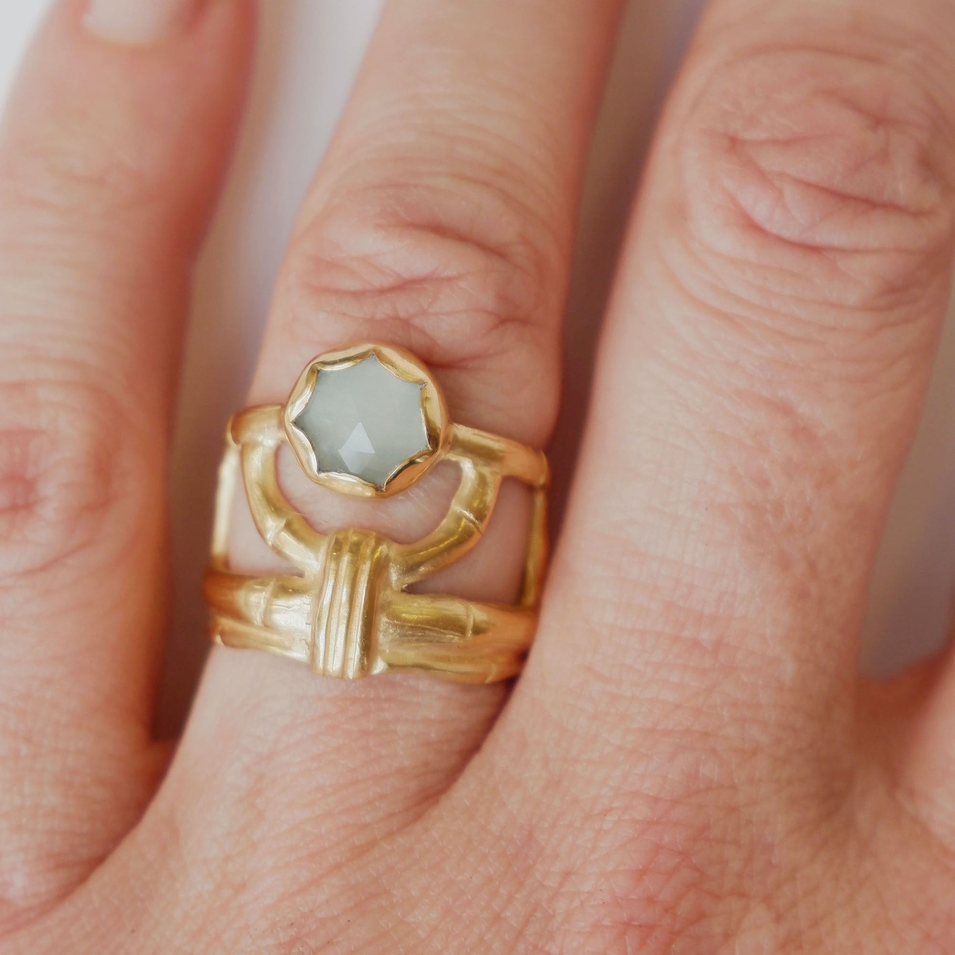 structural open-work ring in a bamboo style, featuring round blue/green cabochon aquamarine gemstone in a scalloped setting. Gold Vermeil. Shown on a hand for scale