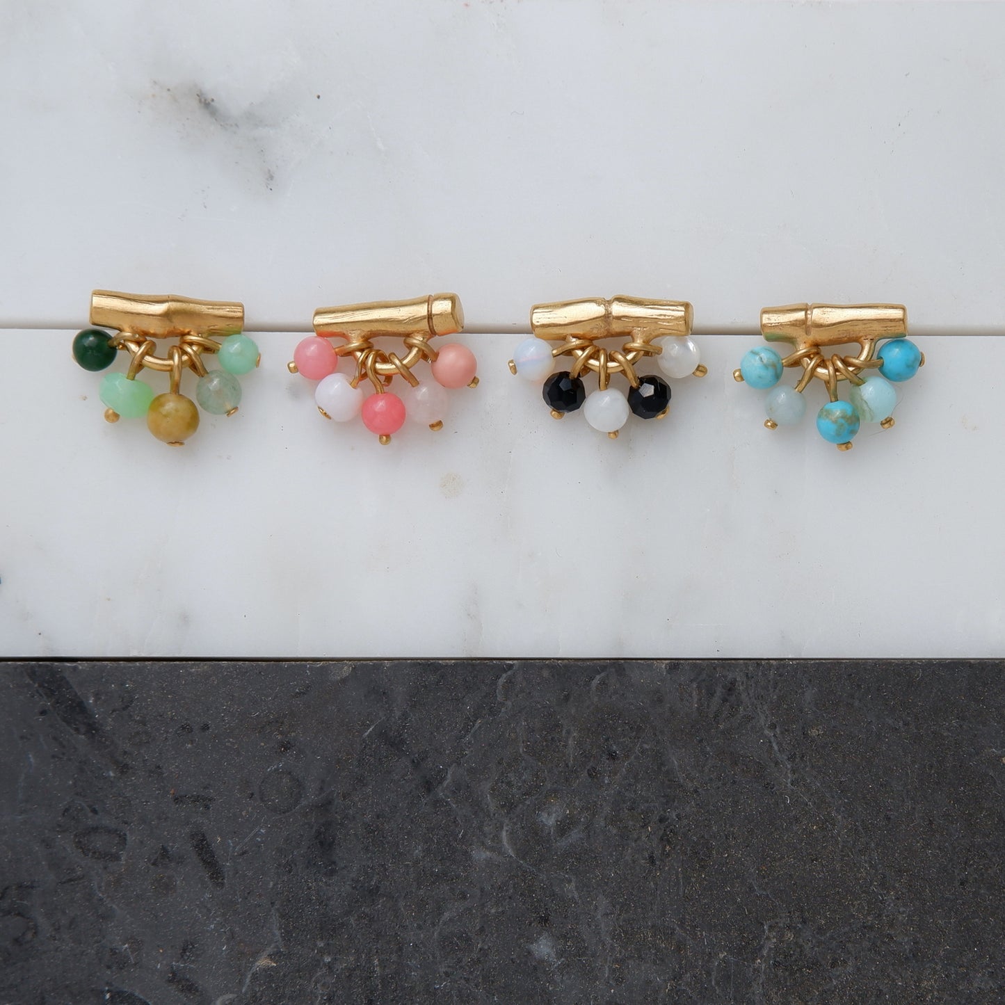 gold vermeil bamboo bar stud earrings with gemstone beads in green, pink, black & white, and green. Still life photograph on marble.