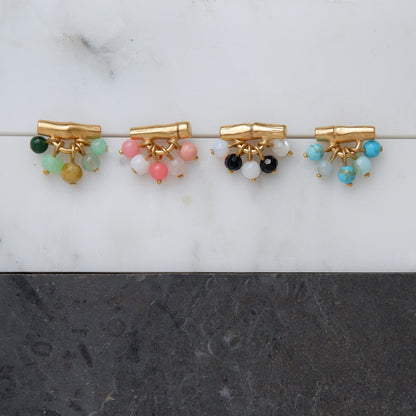 gold vermeil bamboo bar stud earrings with gemstone beads in green, pink, black & white, and green. Still life photograph on marble.