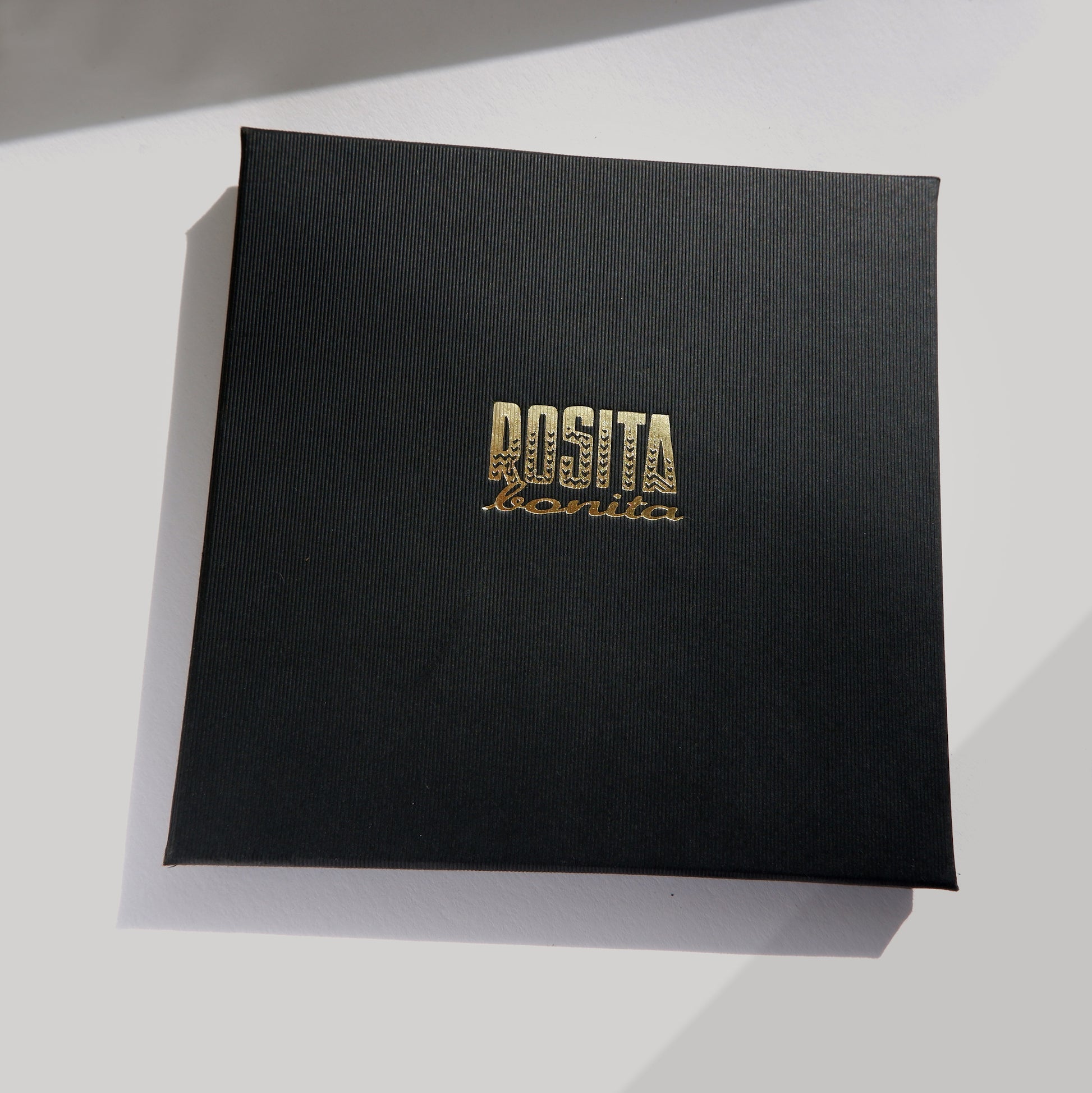 large ribbed black cardboard box with Rosita bonita logo in gold