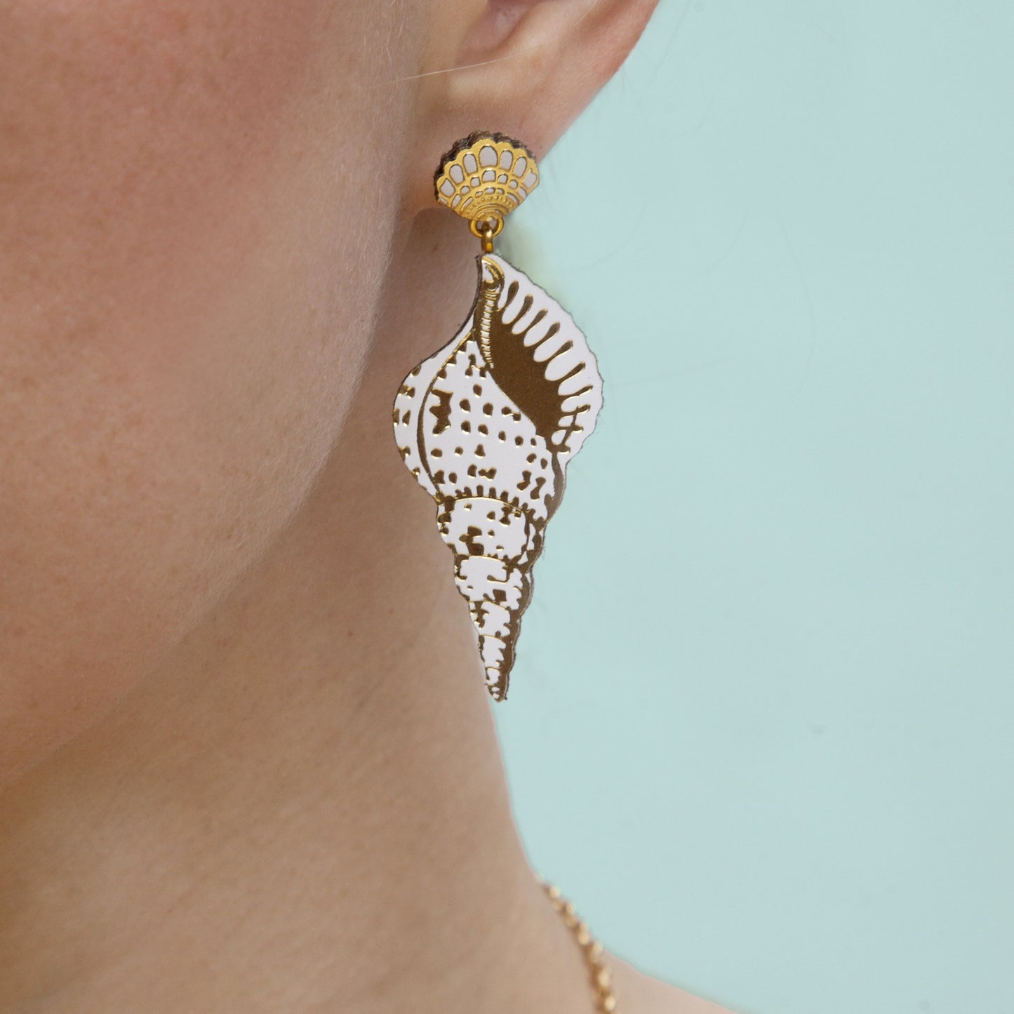 pointy conch shell leather stud earrings in white & gold on model's ear